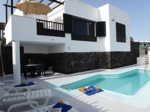 a villa with a swimming pool in front of a house at Villas Don Rafael in Puerto del Carmen