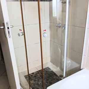 a shower with a glass door in a bathroom at Flamingo Holiday Flats in St Lucia