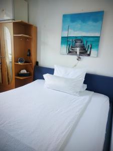 łóżko z białą pościelą i zdjęciem molo w obiekcie Pension Forstgut Waldeck w mieście Ingelheim am Rhein