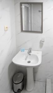 een witte badkamer met een wastafel en een spiegel bij Hotel CARLEONE in Batoemi