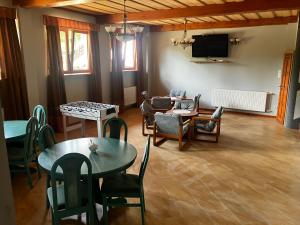 Base Camp Pieniny في Niedzica: غرفة معيشة مع طاولات وكراسي وتلفزيون