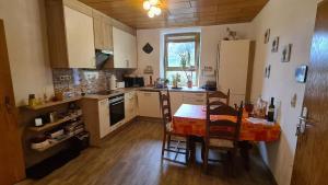 a kitchen with a table and chairs and a refrigerator at FeWo Nitteler Zauberpfoten in Nittel