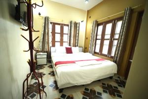 a bedroom with a bed in a room with windows at Hotel Flycatcher Chitwan in Sauraha