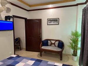 uma sala de estar com uma cadeira e uma televisão em Shaiz Apartments Bhurban, Murree em Murree