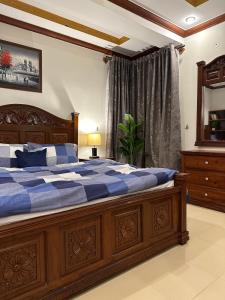 um quarto com uma grande cama de madeira com lençóis azuis em Shaiz Apartments Bhurban, Murree em Murree