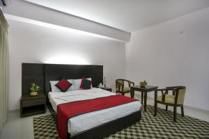 a hotel room with a bed, chair, table and lamps at Nirvana Inn in Sylhet