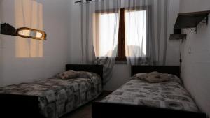 2 Betten in einem Zimmer mit Fenster in der Unterkunft Villetta bordo piscina vista mare Wi-Fi Gratis in Nebida
