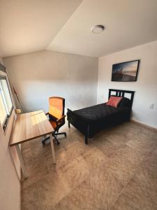 a bedroom with a bed and a desk and a chair at Casa Naranja in Palma de Gandía