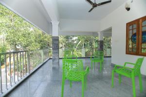Cette chambre dispose de chaises vertes et d'un balcon. dans l'établissement Natureland Homestay, à Kottayam