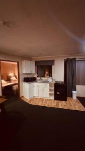 une cuisine avec des placards blancs et une chambre avec un lit dans l'établissement City Court, à Invercargill
