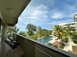 a balcony with a view of a pool and palm trees at By the Sea- Pool and Sea View in Batu Ferringhi