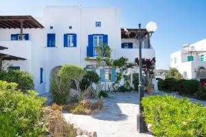 a white building with blue windows and a street light at Charisma House Ornos Beach Mykonos in Mýkonos City