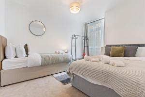 a white bedroom with two beds and a mirror at Cosy Home Next to Wembley Stadium in London