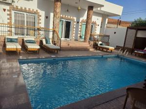 a swimming pool with chairs and a house at Twilight of the Nile in Luxor