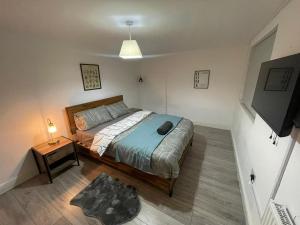 1 dormitorio con cama, mesa y TV en Sweet 7 bedroom Mansion London en Ilford
