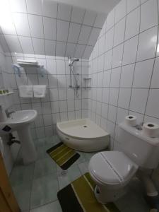 a white bathroom with a toilet and a sink at Vila Riki in Borsec