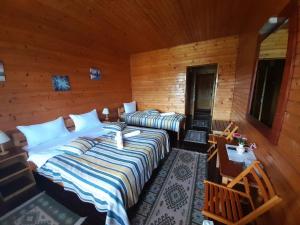 two beds in a room with wooden walls at Vila Riki in Borsec