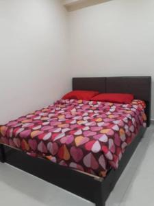 a bed with a colorful comforter and red pillows at Jarzmin 3 Bedroom Apartment in Tanah Rata
