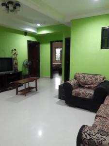 a living room with green walls and a couch and a table at Jarzmin 3 Bedroom Apartment in Tanah Rata
