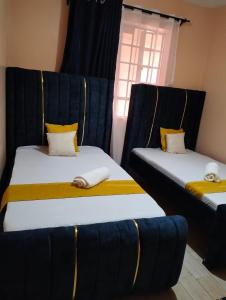 2 łóżka w pokoju z niebieską i żółtą pościelą w obiekcie Elite stay w mieście Embu