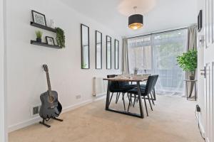 a dining room with a table and a guitar at Cosy Home Next to Wembley Stadium in London