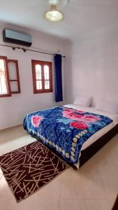 a bedroom with a bed with a blue blanket on it at Warzazat Apartments in Ouarzazate