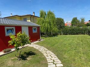a garden with a red house and a stone path at Gondola House in Favaro Veneto