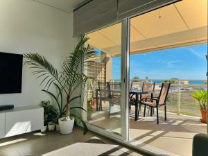 a living room with a balcony with a table and chairs at Apartamento Playa Oliva in Oliva +6 photos