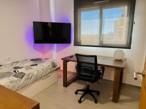 a bedroom with a desk and a chair next to a bed at Apartamento Playa Oliva in Oliva