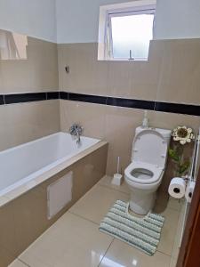 a bathroom with a toilet and a tub and a window at Fifteen Bee in Richards Bay