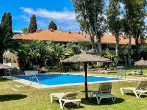 a swimming pool with two chairs and an umbrella at Apartamento Andrea con piscina in Marbella