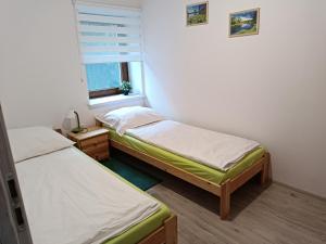 two beds in a small room with a window at Apartament Kristel Zator in Podolsze