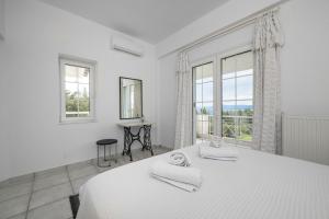 a white bedroom with a large bed and windows at Paliouri Cottage by Luxlikehome in Paliouri