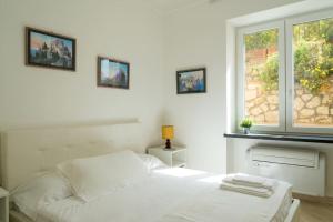 ein weißes Schlafzimmer mit einem Bett und einem Fenster in der Unterkunft Residenza "il sogno di Geppino" al centro di Capri in Capri
