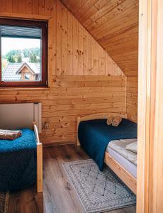 a bedroom with two beds in a wooden cabin at Górskie Chatki Krysi i Piotrka Błękitny in Stronie Śląskie