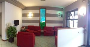 a lobby with red chairs and a waiting room at Hotel Daina in Dalmine