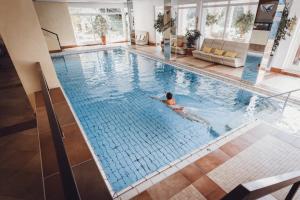 a person swimming in a large swimming pool at Wellnesshotel Sonnenhalde Tonbach in Baiersbronn
