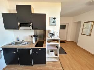 una pequeña cocina con armarios negros y fregadero en Ostseeland, en Barth