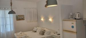 a small white room with a refrigerator and a couch at Anixis Studios Aliki Paros in Aliki