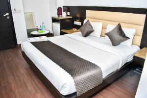 een slaapkamer met een groot bed met witte lakens en kussens bij Hotel Chanchal Continental in New Delhi