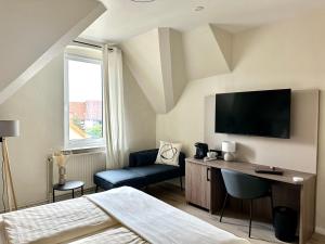 Schlafzimmer mit einem Bett, einem TV und einem Stuhl in der Unterkunft City Hotel Hameln in Hameln