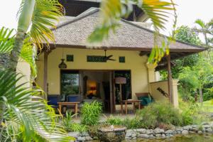 une maison avec une terrasse couverte dotée de chaises bleues dans l'établissement Taman Sari Bali Resort and Spa, à Pemuteran