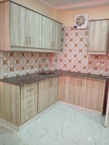 a kitchen with wooden cabinets and a tiled wall at Hotel H6 in Rawalpindi