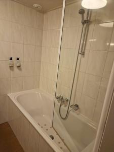 a bathroom with a tub and a shower with a glass door at Hotel Liberte in Schoorl