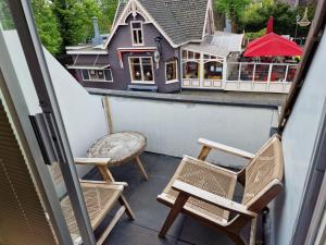 a balcony with chairs and a house in the background at Hotel Liberte in Schoorl