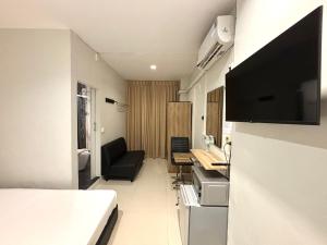 a hotel room with a bed and a television on the wall at Udomsuk Inn & Cafe Since 2019 - BTS Udomsuk in Bangkok