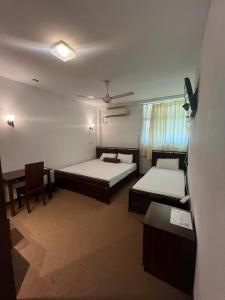 a room with two beds and a chair and a table at Sankara Resort in Ratnapura