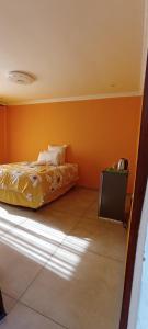 a bedroom with orange walls and a bed and a television at eSunvalley Guest House in Roodepoort