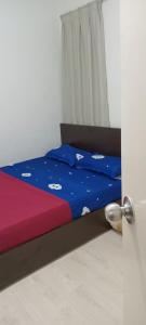 コタキナバルにあるKiena Homestay Uuc 2bilikのベッドルーム1室(青と赤のシーツが備わるベッド1台付)
