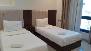 duas camas num quarto de hotel com lençóis brancos em ماجيك سويت الفحيحيل Magic Suite ALFahaheel em Kuwait